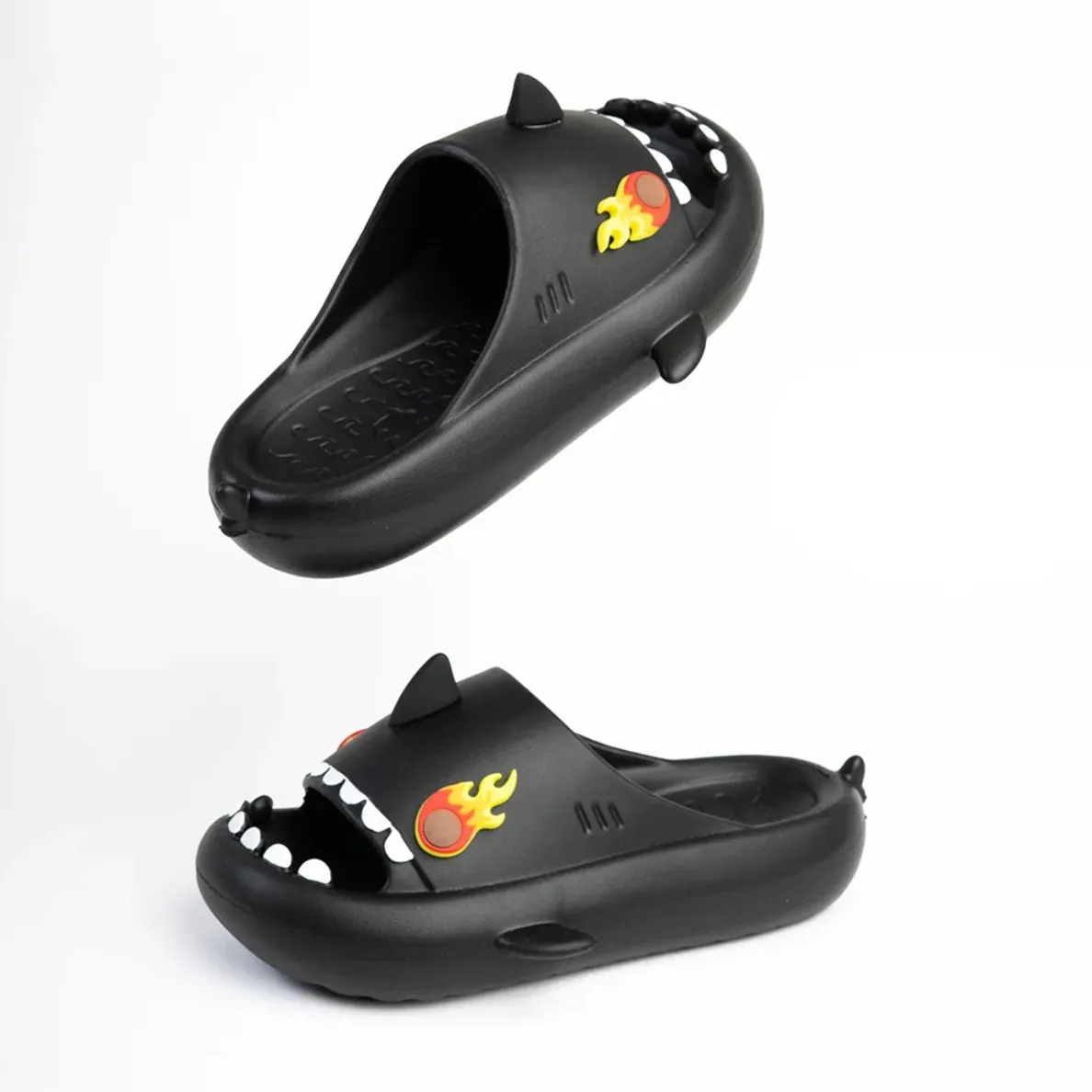 Par de chanclas negras Sharklas modelo Fueguito, con dientes blancos y charm de llama en el empeine.